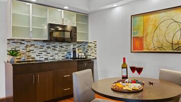 A modern kitchen with dark cabinets, a tiled backsplash, and a dining area with a round table set for a meal.