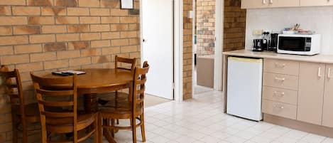 Un espacio habitable compacto con comedor, cocina y un televisor de pantalla plana montado en una pared de ladrillo.