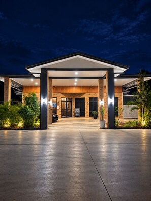 A motel with a reception area, a car parked in front, and a well-lit entrance. - Boulder Opal Motor Inn (Winton)