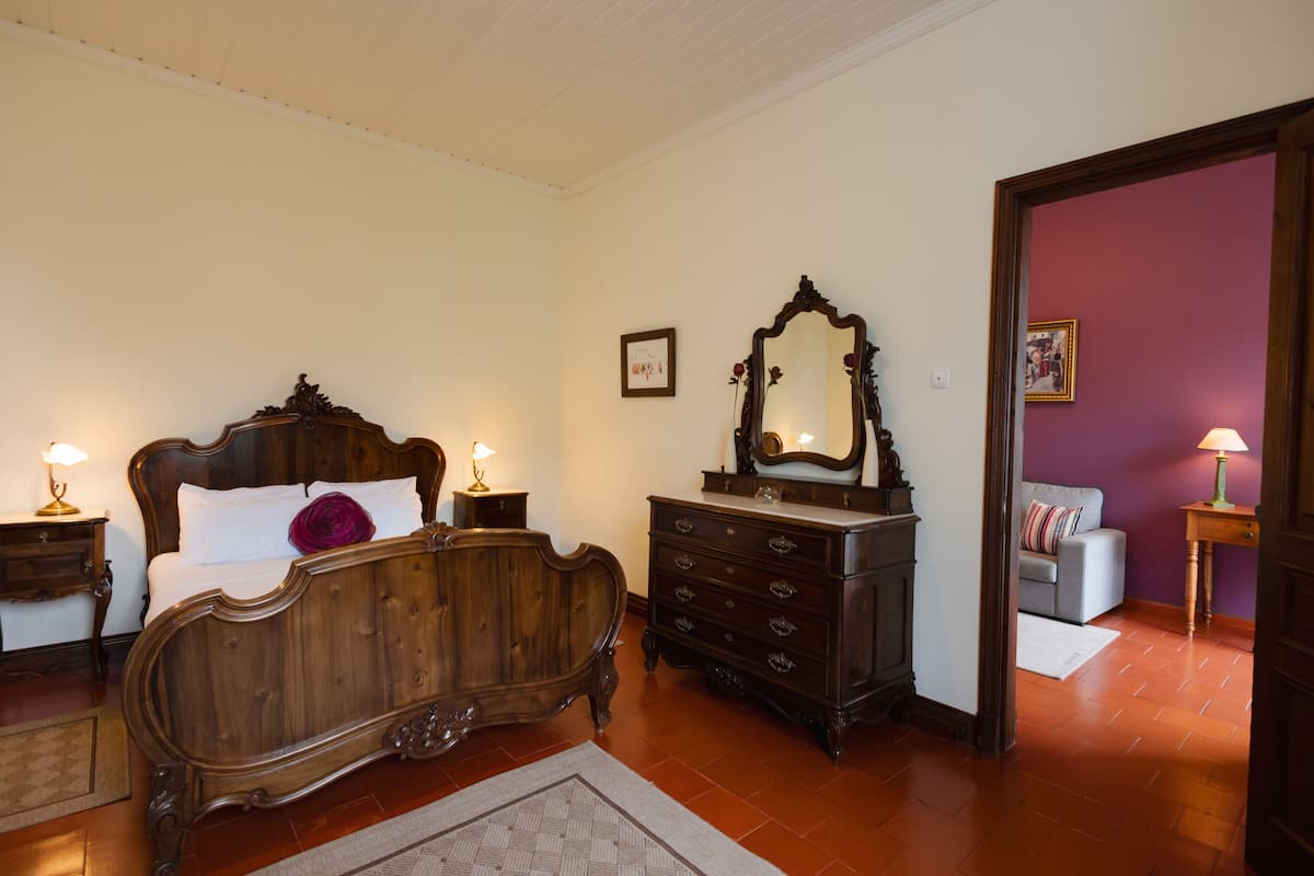 Un dormitorio con una cama de madera, un aparador, un espejo y un sofá.