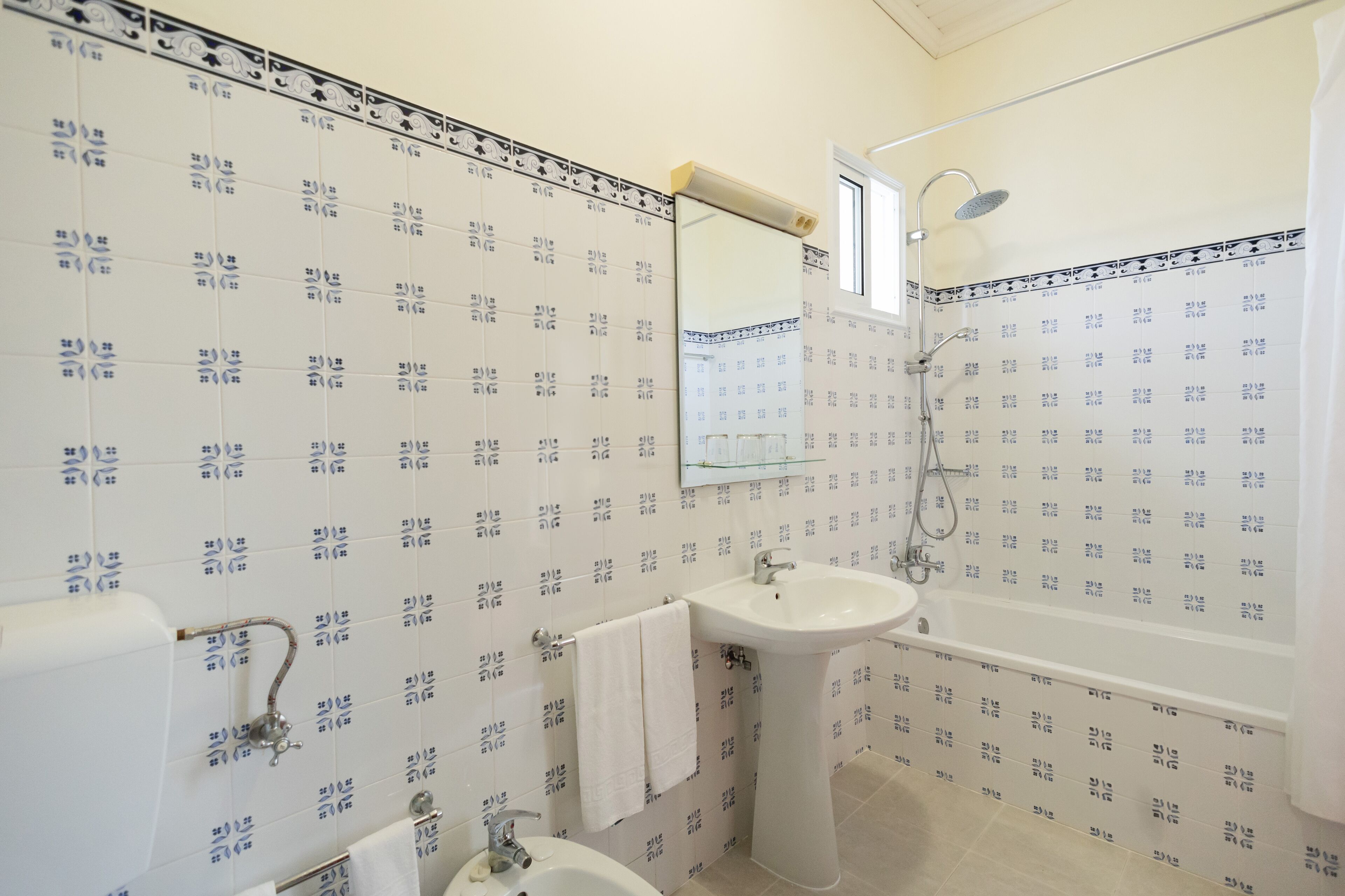 A bathroom with patterned tiles, a sink, a bathtub, and a mirror.