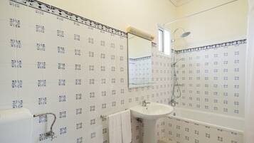 A bathroom with patterned tiles, a sink, a bathtub, and a mirror.