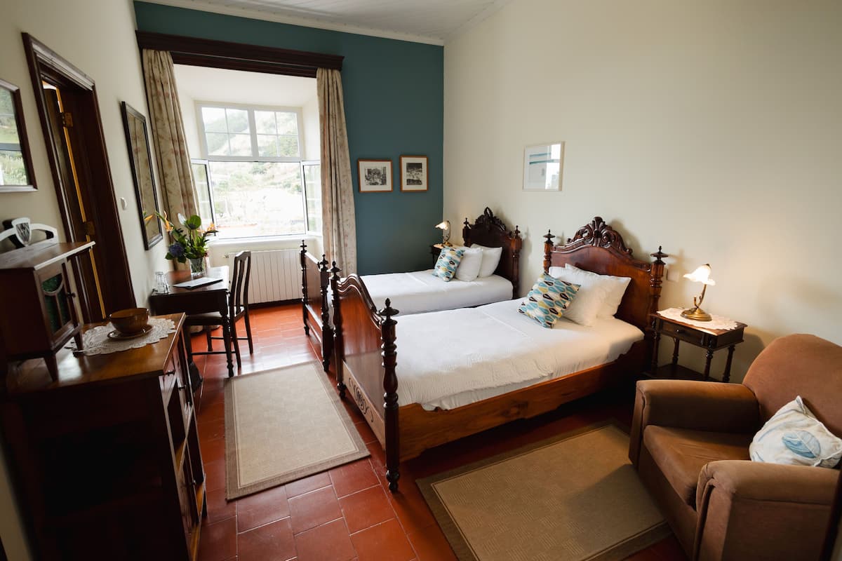 Un dormitorio con una cama de madera, un escritorio, una silla y una ventana con cortinas.