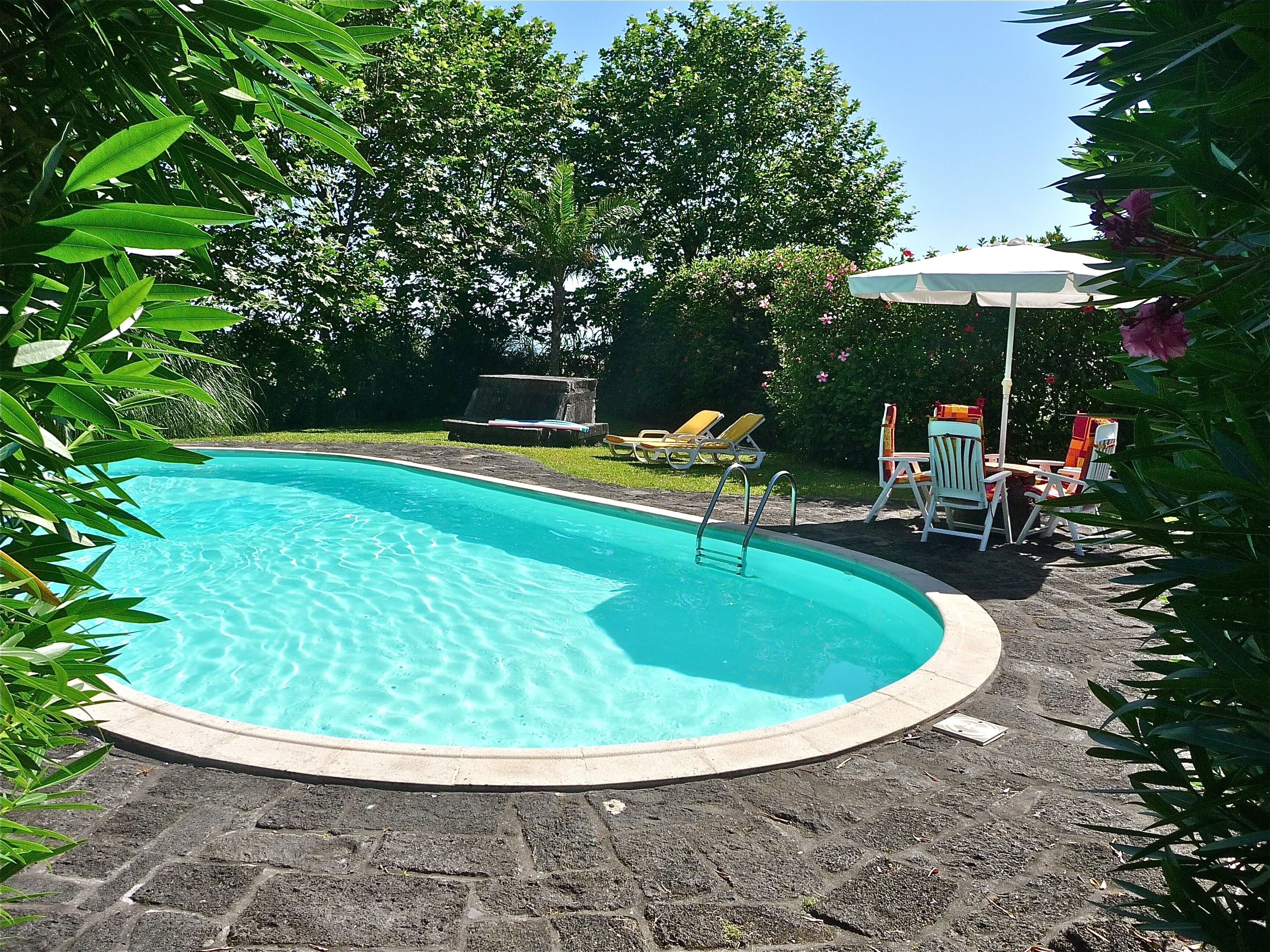 Una piscina al aire libre, sombrillas, sillones reclinables de piscina