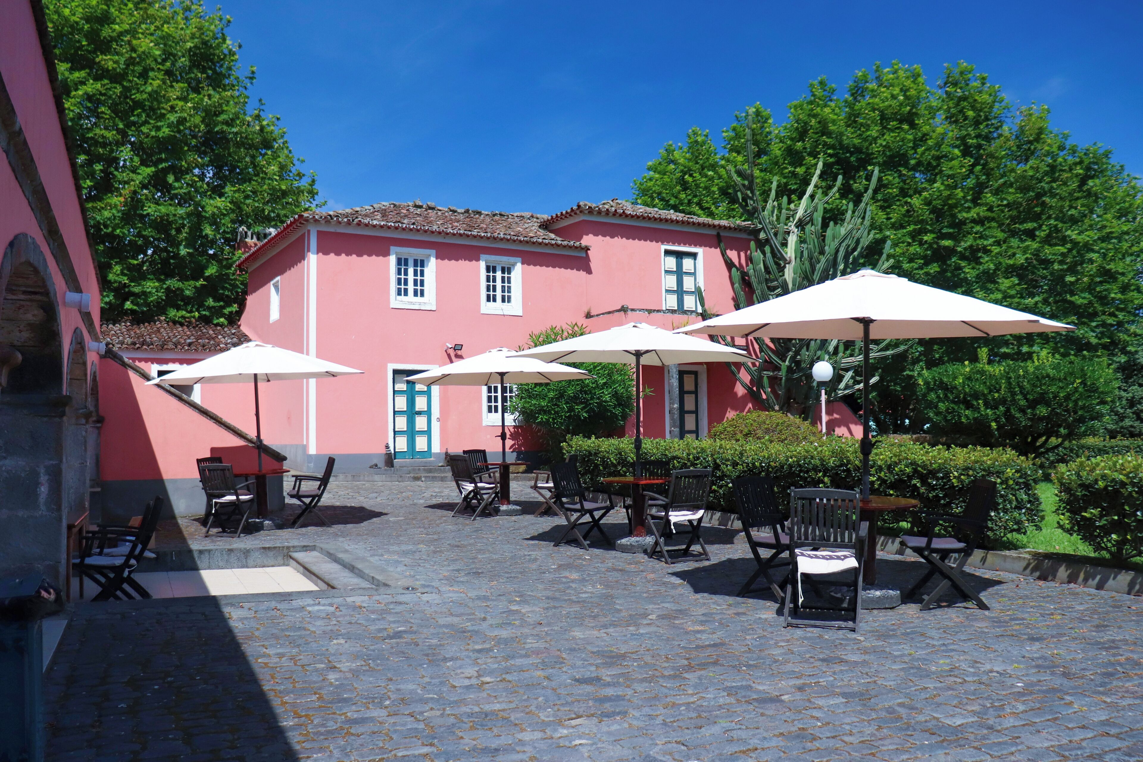 Eine Terrassengrundstueck mit Steinplattenboden, Sitzgelegenheiten mit Tischen und Stühlen sowie Sonnenschuermen.