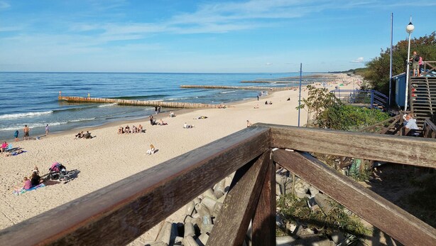 Una playa con pasarelas de madera y una vista despejada del océano.