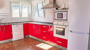 A kitchen with red cabinets, a dishwasher, a microwave, and an oven. - Lovely home in Barbate with WiFi (Barbate)