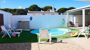 A backyard with a swimming pool, artificial grass, and white lounge chairs. - Lovely home in Barbate with WiFi (Barbate)