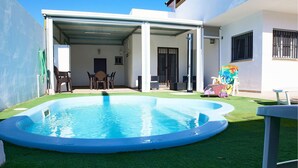 A residential backyard with a swimming pool, a covered patio, and a small garden area. - Lovely home in Barbate with WiFi (Barbate)