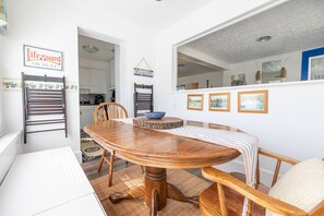 Ein Essbereich mit Holztisch und Stühlen, einem weißen Kühlschrank und einer sichtbaren Küche im Hintergrund.