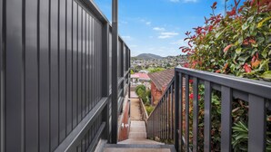Een trap die leidt naar een balkon met uitzicht op een stadsbeeld en bergen in de verte.