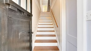 A staircase with white walls and wooden steps leading to a room. - Updated 1930s carriage house in Ardsley Park (Savannah)