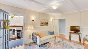 A living room with a sofa, coffee table, TV, and a patterned rug. - Updated 1930s carriage house in Ardsley Park (Savannah)