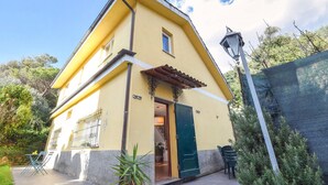A yellow building with a green door, a small balcony, and a street lamp.