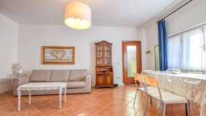 A living room with a sofa, a small table, a cabinet, and a dining area with chairs and a table.