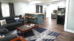 A living room with a sofa, coffee table, and a bar area with stools.