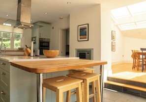 A modern kitchen with a central island, wooden stools, and a dining area with a table and chairs. - Spectacular views over Newport Bay, Parrog, Nevern Estuary, and the Preseli Mountains (Newport)