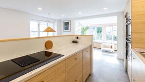 Une cuisine moderne dotée d’un îlot central, de meubles en bois et d’un four encastré.