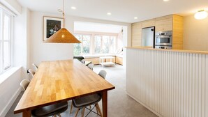 Une cuisine moderne dotée d’un plan de travail en bois, d’appareils électroménagers intégrés et d’un coin repas avec une table et des chaises en bois.