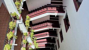 Ein mehrgeschossiges Gebäude mit einer zentralen Treppe, Blumentöpfen und einem dekorativen Metallgeländer.