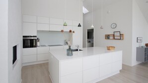 Una cocina moderna con armarios blancos, una isla central y un pequeño comedor.
