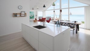 Una cocina moderna con una isla central, ventanas amplias y vista al mar.