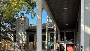 A two-story building with a covered porch and a red door. - Mountain Hideaway - Hot Tub, 3 Living Areas, 5 min. to Shop/Ski (Park City)
