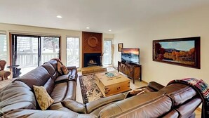 A spacious living room with a large leather sofa, a fireplace, a television, and a framed landscape painting. - Mountain Hideaway - Hot Tub, 3 Living Areas, 5 min. to Shop/Ski (Park City)