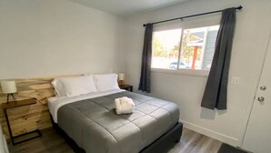 A bedroom with a bed, a nightstand, a window with curtains, and a door. - 3BR Park Ave Townhome (Park City)