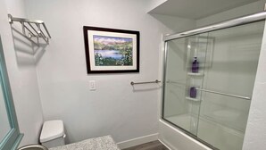 A bathroom with a granite countertop sink, a toilet, a framed landscape painting, and a glass shower enclosure. - 3BR Park Ave Townhome (Park City)