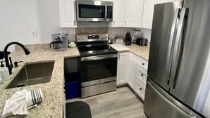 A modern kitchen with white cabinets, stainless steel appliances, a granite countertop, and a built-in oven. - 3BR Park Ave Townhome (Park City)