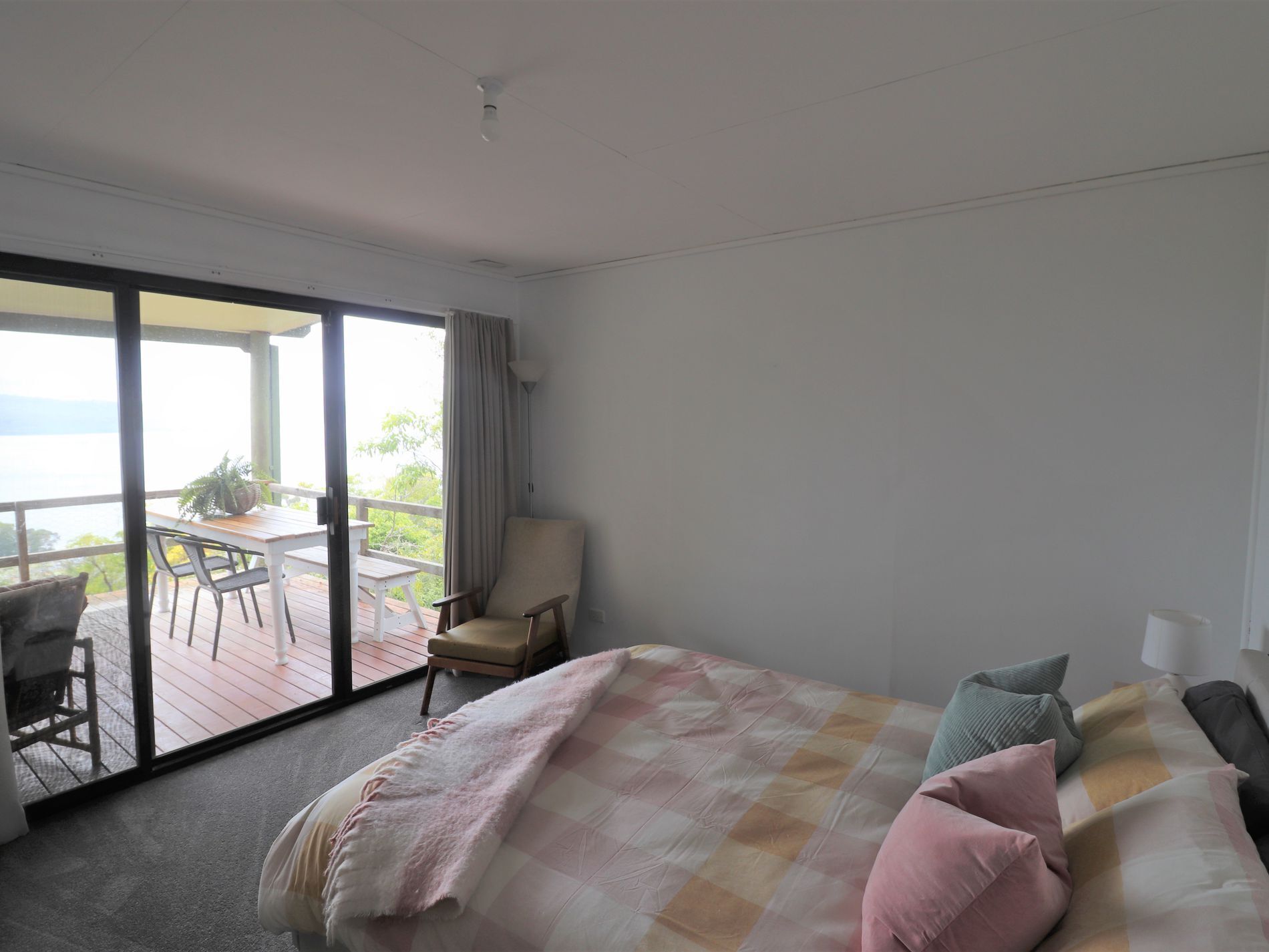 Une chambre avec un grand lit, une chaise, une table et une vue sur l’extérieur.