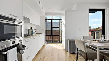 A modern kitchen with white cabinetry, a Bosch oven, and a dining area with a table and chairs.