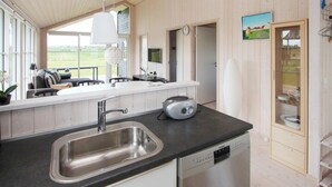 A modern kitchen with a stainless steel sink, a Bosch dishwasher, and a large window offering a view of the outdoors.