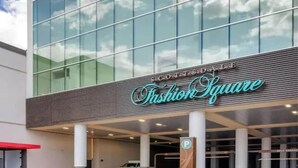 A building with a sign reading "Fashion Square" and a parking sign.