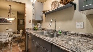 Eine Küche mit Granit-Arbeitsplatten, Edelstahlspülen und einer Pendelleuchte.