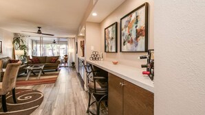 A modern kitchen with a bar area, a dining area with a sofa and chairs, and a view through the glass door. - Cozy 2-bdrm Condo in Heart of Old Town Scottsdale! (Scottsdale)