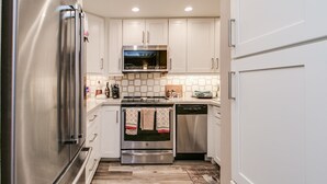 A kitchen with stainless steel appliances, white cabinetry, and a tiled backsplash. - Cozy 2-bdrm Condo in Heart of Old Town Scottsdale! (Scottsdale)
