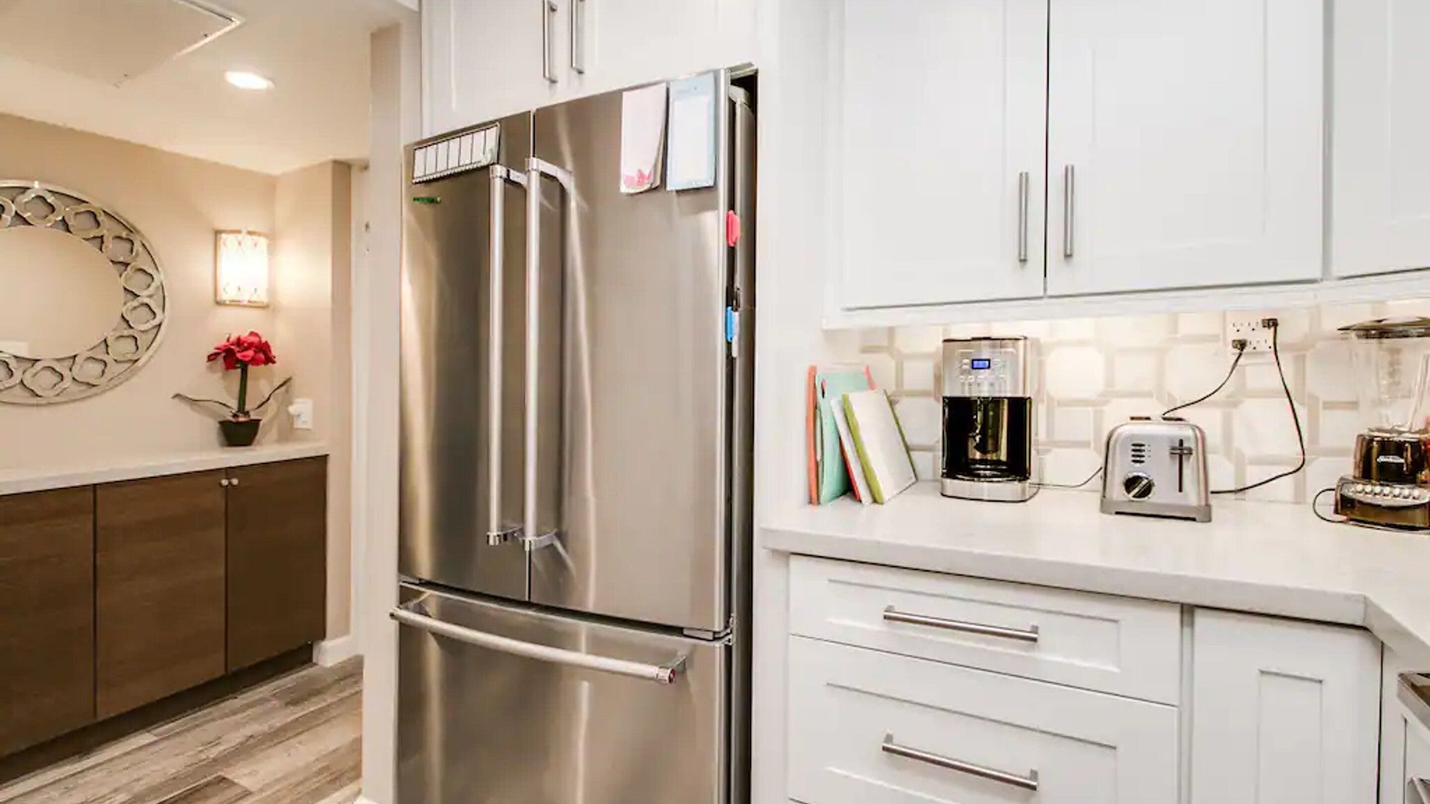 A modern kitchen with stainless steel appliances, white cabinetry, and a coffee maker on the counter.