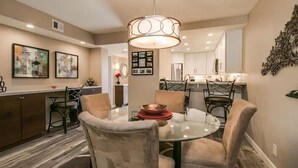 A modern dining area with a glass table, four chairs, and a central light fixture. - Cozy 2-bdrm Condo in Heart of Old Town Scottsdale! (Scottsdale)