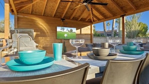 An outdoor dining area with wooden tables, chairs, and a ceiling fan. - Just Listed! Old Town Paradise W/htd Pool & Spa! (Scottsdale)