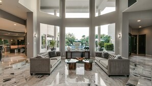 A spacious living area with a marble floor, two sofas, a coffee table, and a view of a garden through large windows. - Stunning Private & Modern N. Scottsdale Estate! (Scottsdale)