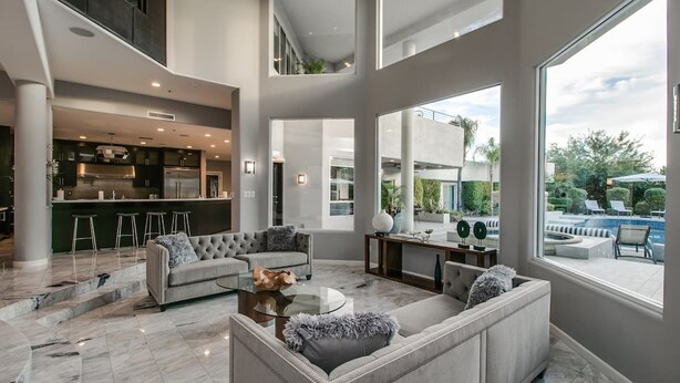 A spacious living area with a modern kitchen, a comfortable seating arrangement, and a view of a swimming pool. - Stunning Private & Modern N. Scottsdale Estate! (Scottsdale)