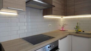 Une cuisine moderne avec des carreaux de métro blancs, des armoires en bois, une hotte en acier inoxydable et un four encastré.