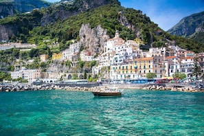A coastal town with colorful buildings, a clear blue sea, and a boat in the foreground. - Campanella s Studios - Comfort in the Nature (Massa Lubrense)