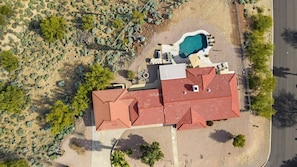 Eine Luftaufnahme eines Hauses mit rotem Dach, einem Schwimmbad und einer Wüstenlandschaft.