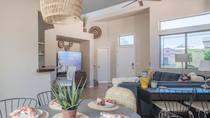 A spacious living area with a dining table set for two, a sofa, and a television.