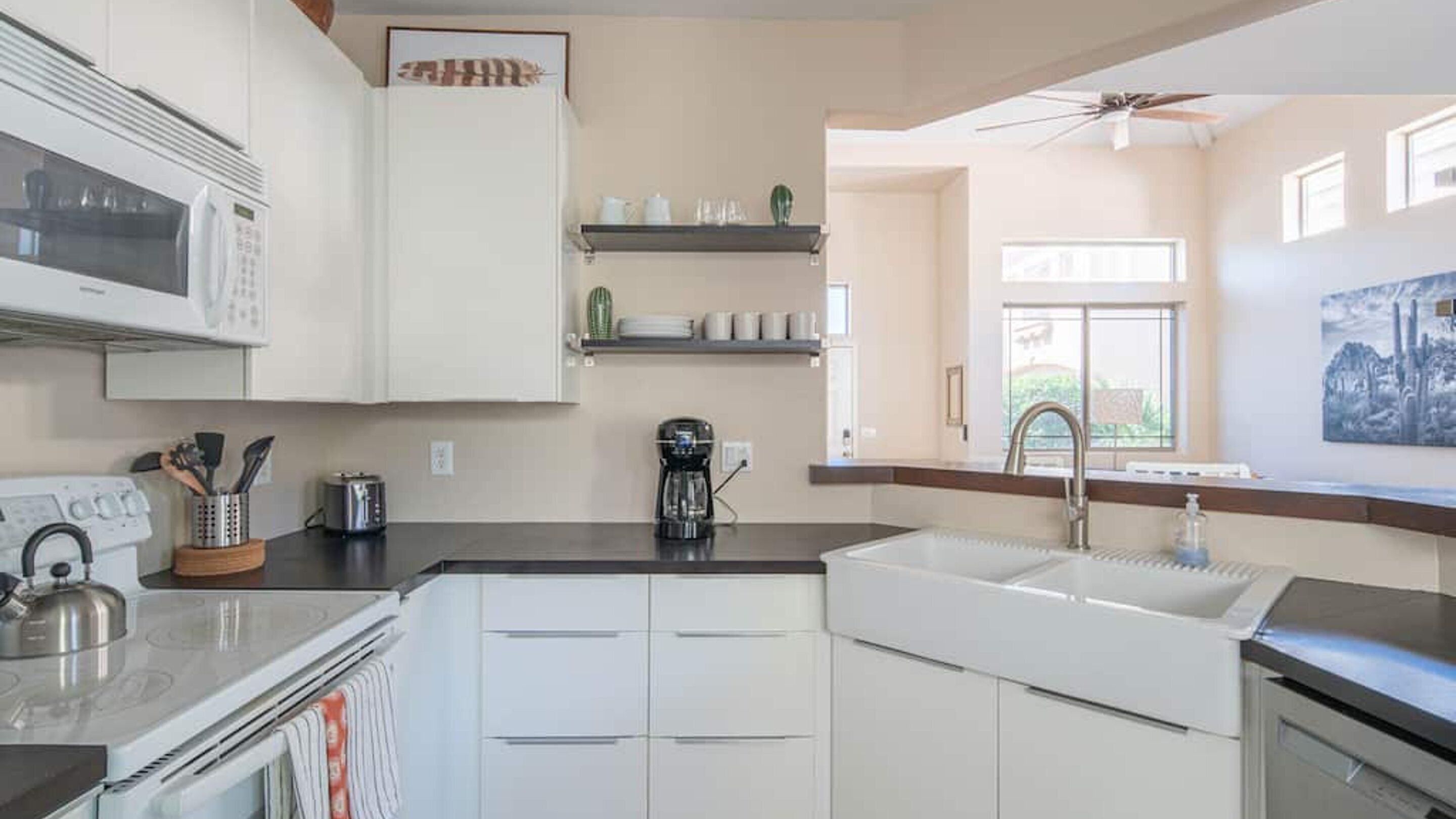 A modern kitchen with white cabinets, a microwave, a coffee maker, and a sink.