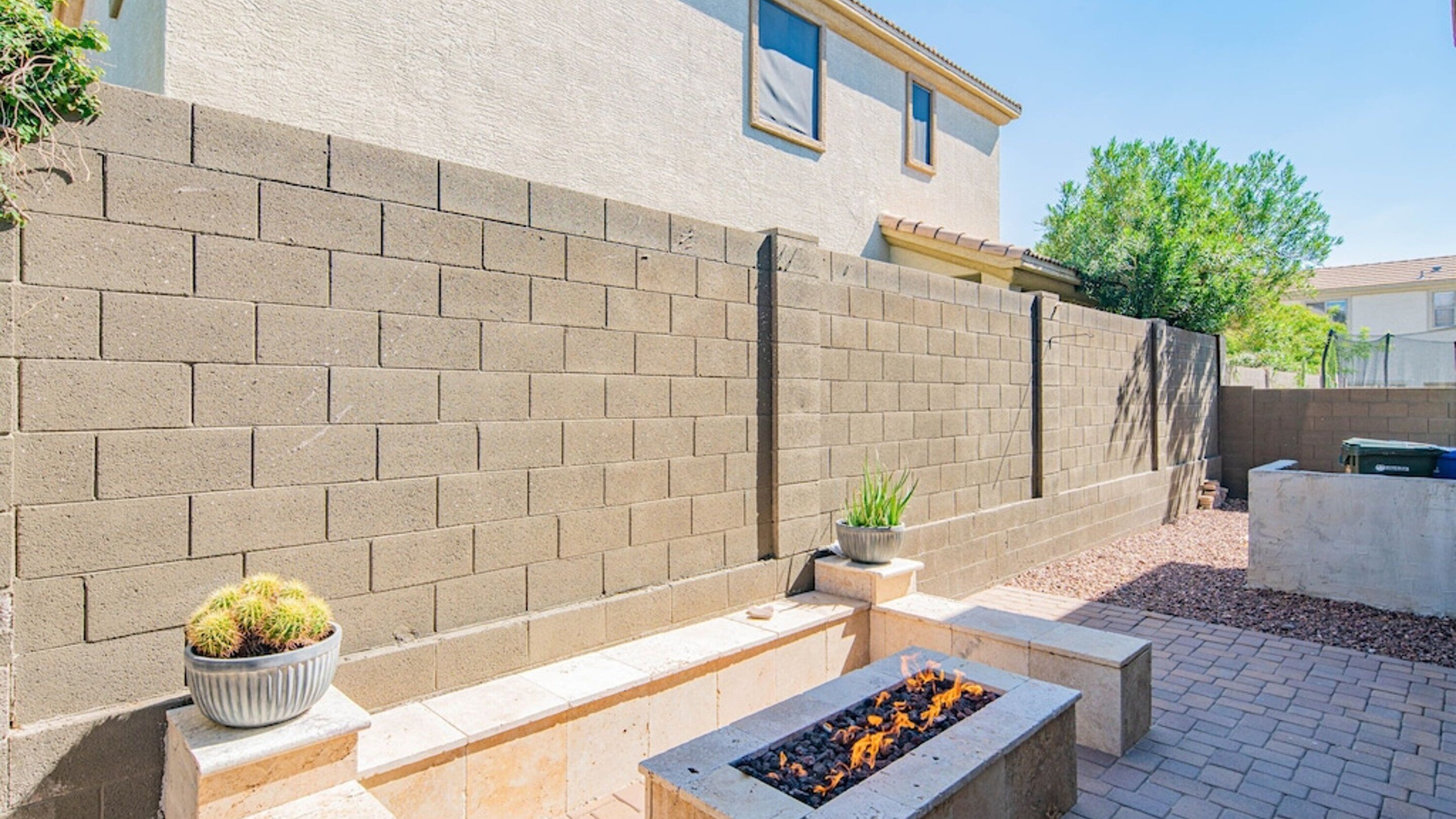 A brick wall with a fire pit and potted plants.
