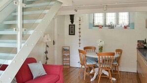 A modern interior with a staircase, a red sofa, a dining table with chairs, and a kitchen area. - Church Conversion 3-bed House in Centre of Kendal (Kendal)